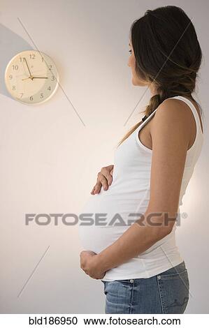 Stock Image - Pregnant Caucasian woman watching clock. Fotosearch