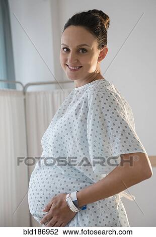 Stock Image - Pregnant Caucasian woman wearing hospital gown. Fotosearch