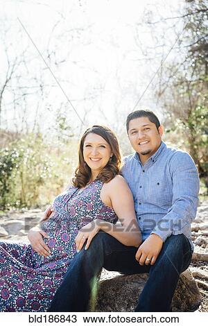 Stock Image - Pregnant Hispanic couple smiling outdoors. Fotosearch