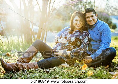 Stock Photo - Pregnant Hispanic couple smiling outdoors. Fotosearch