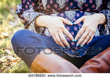 Stock Image - Pregnant Hispanic woman holding her belly. Fotosearch