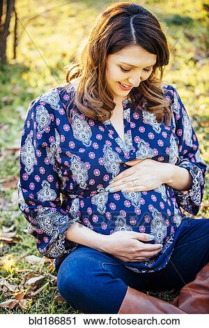 Stock Image - Pregnant Hispanic woman holding her belly. Fotosearch