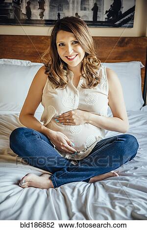Stock Image - Pregnant Hispanic woman holding her belly. Fotosearch