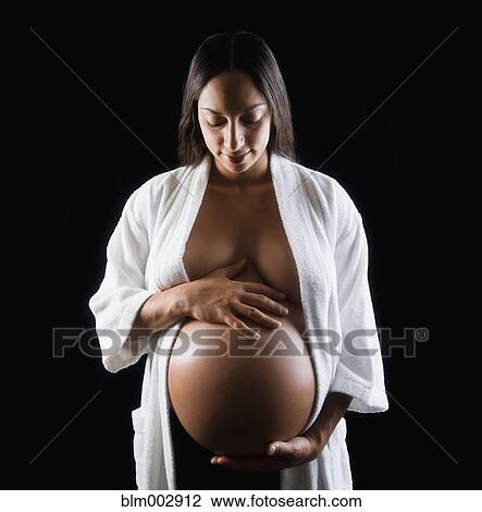 Stock Image - Pregnant Middle Eastern woman holding bare stomach. Fotosearch