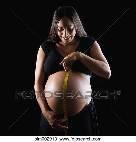 Stock Image - Pregnant Middle Eastern woman measuring stomach. Fotosearch