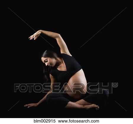 Stock Photography - Pregnant Middle Eastern woman stretching on floor. Fotosearch
