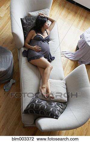 Stock Image - Pregnant mixed race woman relaxing in living room. Fotosearch