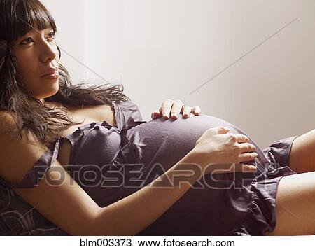 Stock Image - Pregnant mixed race woman relaxing. Fotosearch