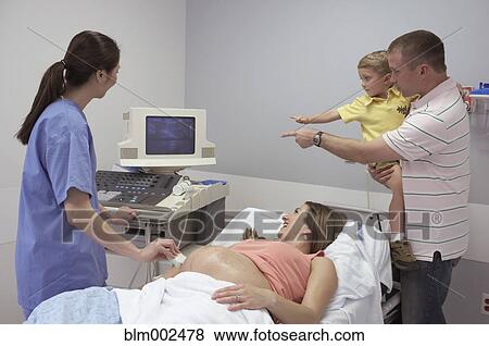 Stock Photo - Pregnant woman and family looking at ultrasound. Fotosearch