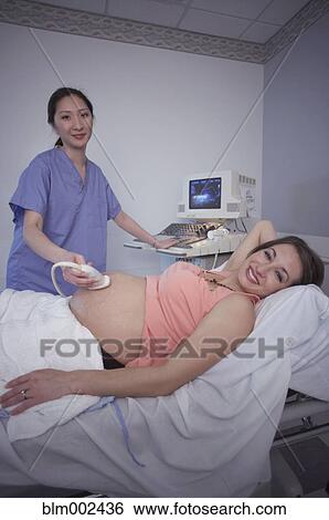 Stock Photograph - Pregnant woman having ultrasound procedure. Fotosearch