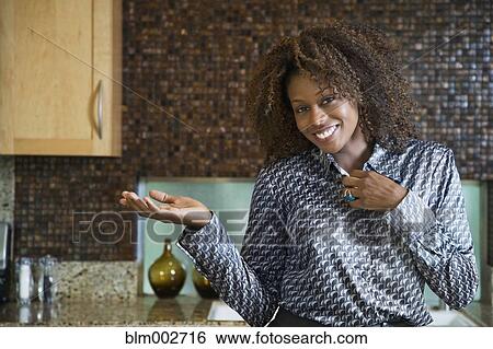 Stock Photograph - Proud African woman showing off modern kitchen. Fotosearch