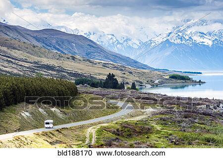 Stock Image - RV driving near mountains and lake in remote landscape. Fotosearch