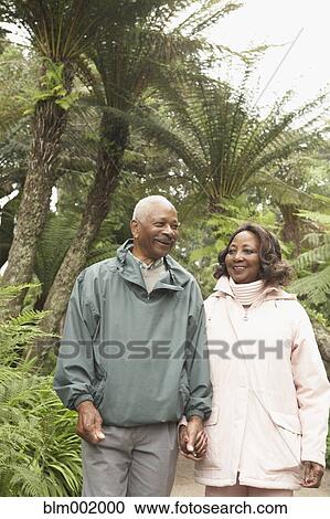 Stock Image - Senior African couple holding hands and walking outdoors. Fotosearch