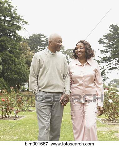 Stock Photo - Senior African couple holding hands and walking outdoors. Fotosearch