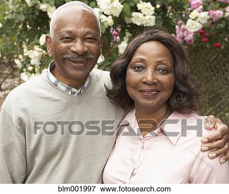 Stock Photo - Senior African couple hugging and smiling outdoors. Fotosearch