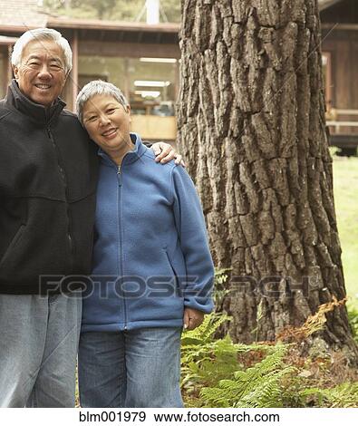 Stock Photo - Senior Asian couple hugging and smiling outdoors. Fotosearch