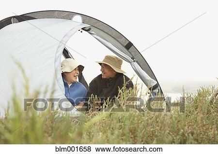 Stock Photo - Senior Asian couple sitting in tent smiling. Fotosearch