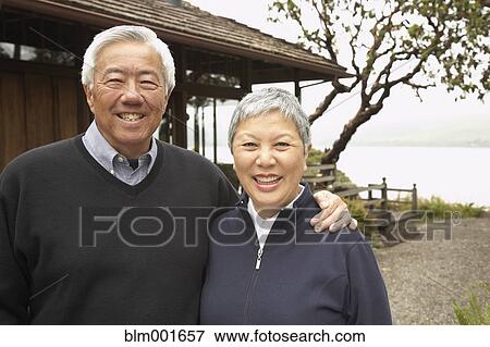 Stock Photo - Senior Asian couple smiling and hugging outdoors. Fotosearch