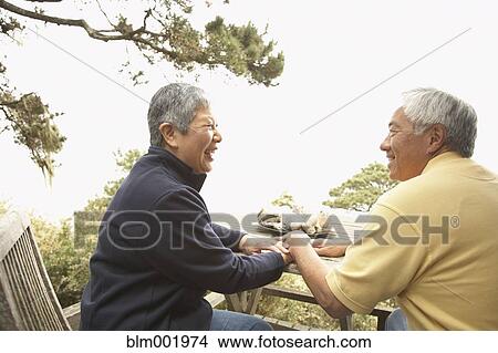 Picture - Senior Asian couple talking and laughing outdoors. Fotosearch