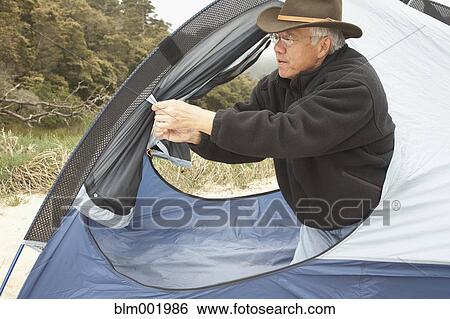 Stock Photograph - Senior Asian man opening tent. Fotosearch