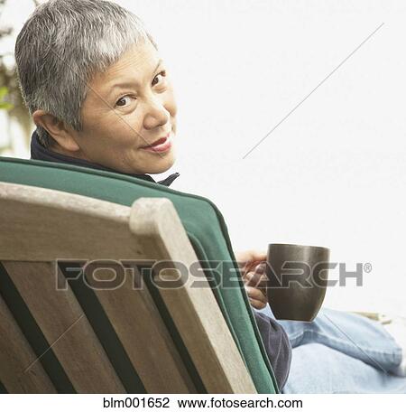 Senior Asian woman sitting outdoors with coffee View Large Photo Image Stock Image - Senior Asian woman sitting outdoors with coffee. Fotosearch