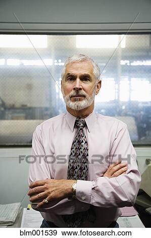 Stock Photo - Senior businessman with warehouse in background. Fotosearch
