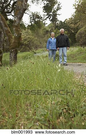 Stock Image - Senior couple holding hands outdoors. Fotosearch