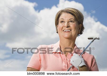 Stock Photo - Senior Hispanic woman holding golf club. Fotosearch