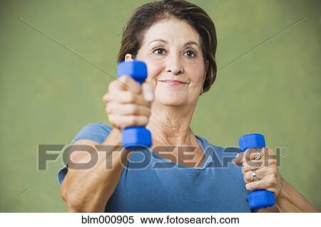 Stock Photography - Senior Hispanic woman lifting hand weights. Fotosearch