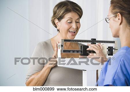 Stock Photo - Senior Hispanic woman on medical scale. Fotosearch