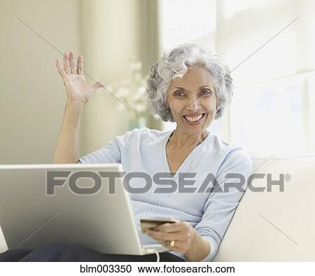 Senior Hispanic woman on sofa with laptop and credit card View Large Photo Image Stock Image - Senior Hispanic woman on sofa with laptop and credit card. Fotosearch