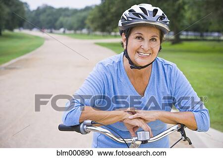 Stock Image - Senior Hispanic woman riding bicycle. Fotosearch
