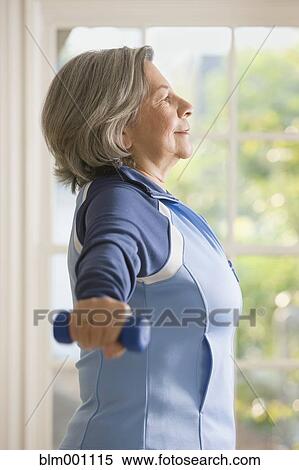 Stock Photography - Senior Hispanic woman working out with hand weights. Fotosearch