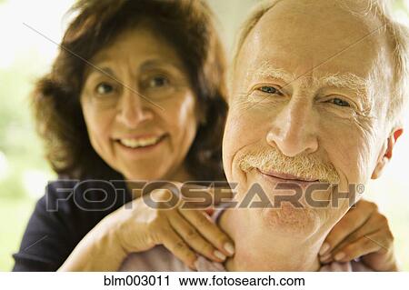 Stock Image - Senior woman giving husband a neck rub. Fotosearch