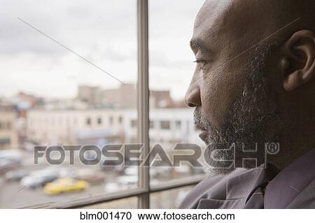 Serious African businessman looking out window View Large Photo Image Stock Image - Serious African businessman looking out window. Fotosearch