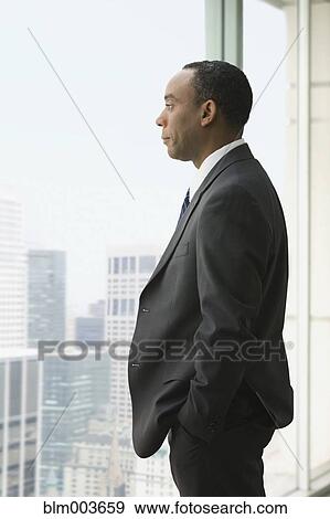 Stock Photo - Serious African businessman looking out window. Fotosearch