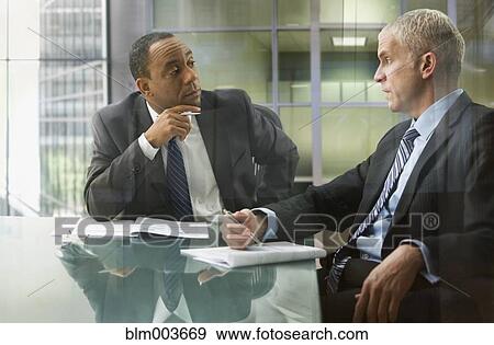 Serious businessmen reviewing documents in meeting View Large Photo Image Stock Photo - Serious businessmen reviewing documents in meeting. Fotosearch