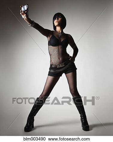 Stock Image - Sexy Hispanic woman in fishnet shirt taking self-portrait. Fotosearch