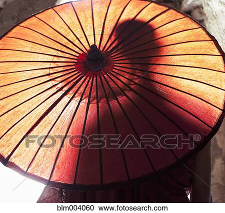 Stock Image - Silhouette of Asian man behind sun umbrella. Fotosearch