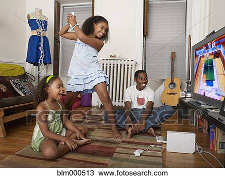 Stock Image - Sisters playing video games in living room. Fotosearch