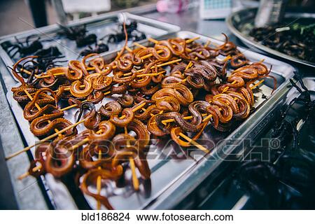 Picture - Skewered snakes cooking on grille. Fotosearch