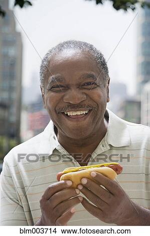 Smiling African man holding hot dog View Large Photo Image Picture - Smiling African man holding hot dog. Fotosearch