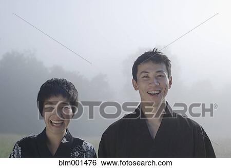 Smiling Asian couple in robes standing in field View Large Photo Image Stock Photograph - Smiling Asian couple in robes standing in field. Fotosearch