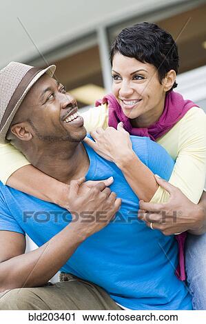 Stock Image - Smiling couple hugging outdoors. Fotosearch