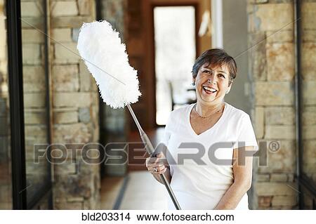 Picture - Smiling Hispanic woman holding duster. Fotosearch