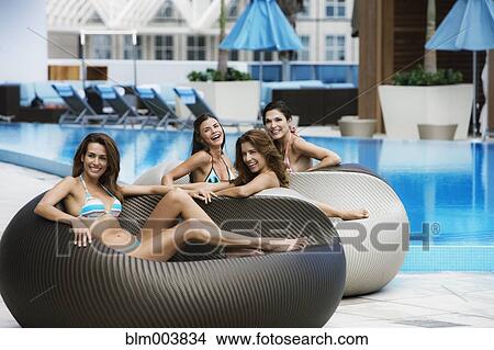 Picture - Smiling Hispanic women in poolside chairs. Fotosearch