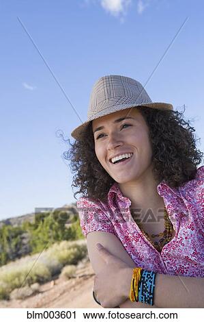 Stock Image - Smiling mixed race woman wearing fedora. Fotosearch
