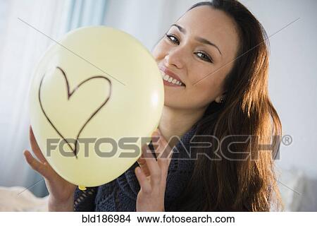 Picture - Smiling woman holding balloon. Fotosearch
