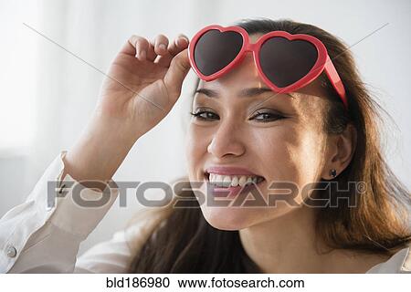 Smiling woman wearing heart shaped sunglasses View Large Photo Image Stock Image - Smiling woman wearing heart shaped sunglasses. Fotosearch
