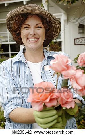 Stock Image - Smiling woman working in garden. Fotosearch